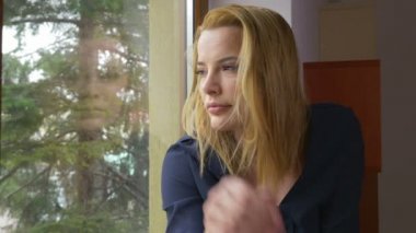 Pencereden dışarı bakarak ve bekleyen genç üzgün kadın