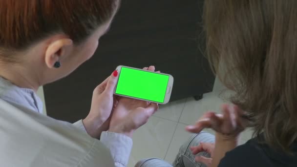 Dos mujeres de negocios sosteniendo un smartphone con pantalla verde — Vídeos de Stock