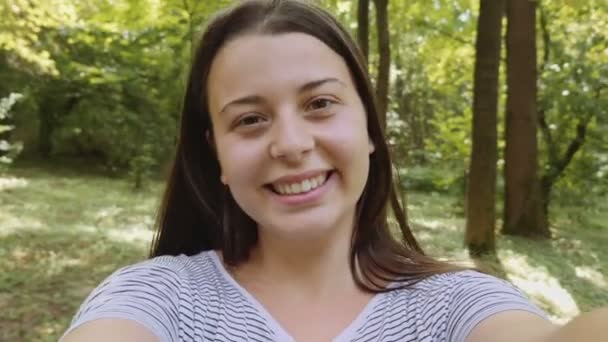 Feliz joven mujer tomando selfie en el parque — Vídeo de stock