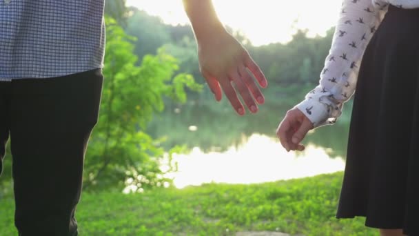 Close-up de casal de mãos dadas ao pôr do sol e caminhando juntos — Vídeo de Stock