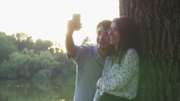 Happy couple taking selfie with the smartphone in the park — Stock Video