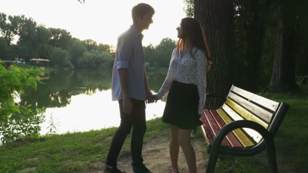 Pareja romántica caminando en el parque y sentada en un banco — Vídeo de stock