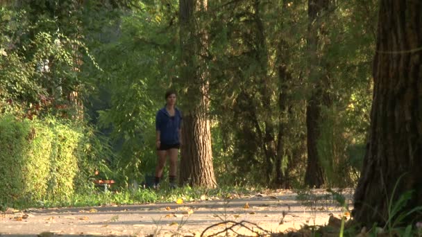 Mooi meisje rolschaatsen in een park — Stockvideo