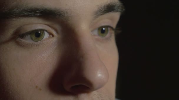 Close-up of a young man eyes in the dark watching TV — Stock Video