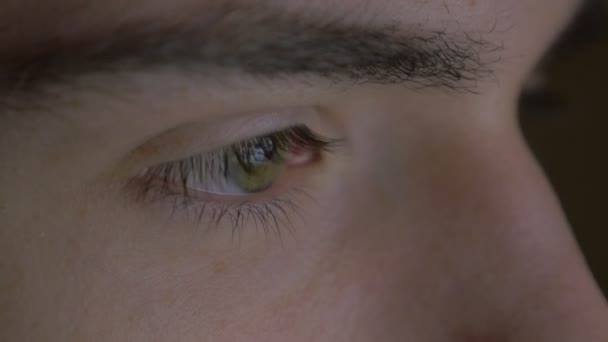 Крупный план глаза молодого человека, просматривающего планшетный компьютер — стоковое видео