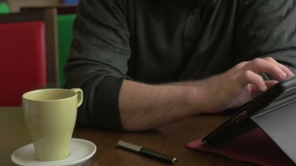 Uomo d'affari che lavora su un tablet pc e beve caffè in una caffetteria — Video Stock