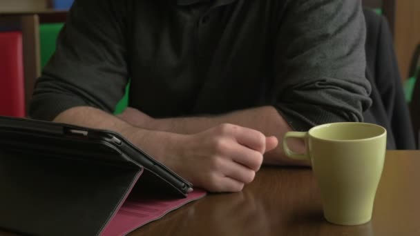 Zakenman werken op een tablet pc en drinken koffie in een koffieshop — Stockvideo