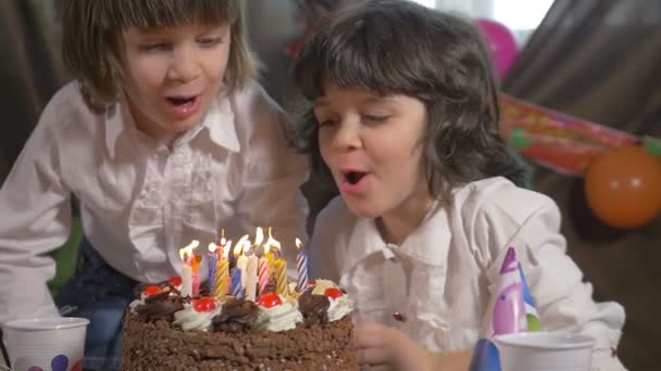 Jonge mooie twin zusters blazen kaarsen op een verjaardag cake, slow-motion — Stockvideo