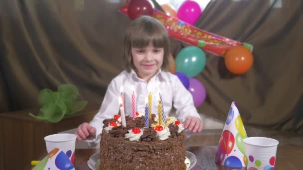 Menina bonita nova soprando velas em um bolo de aniversário — Vídeo de Stock