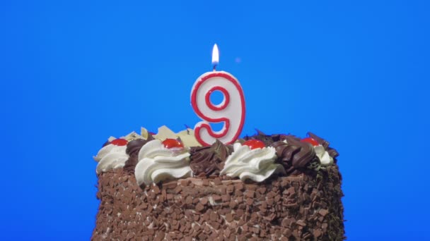 Soplando la vela número nueve cumpleaños en un delicioso pastel de chocolate, pantalla azul — Vídeos de Stock