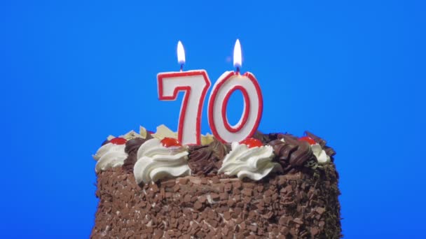 Blåser ut nummer sjuttio födelsedag ljusen på en läcker chokladkaka, blå skärm — Stockvideo