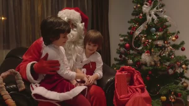Jóvenes hermosas chicas gemelas sentadas en el regazo de Santa Claus en el día de Navidad - 4k — Vídeos de Stock