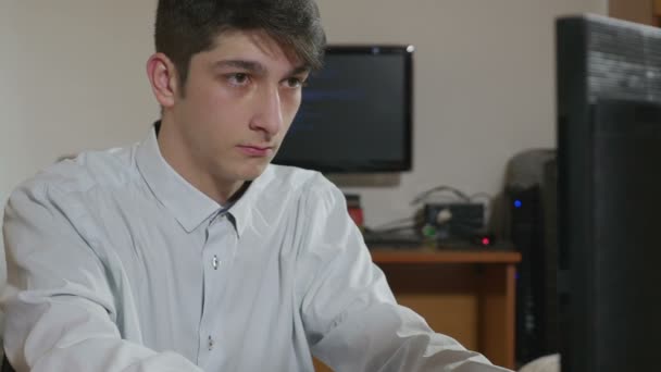 Schöner junger Programmierer, der an zwei Computern programmiert — Stockvideo