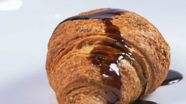 Yavaş çekimde bir kruvasan kapsayan lezzetli eritilmiş çikolata şurubu