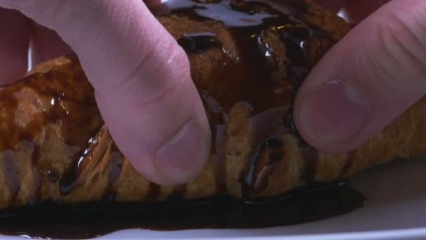 Homme mains cassant un croissant recouvert de délicieux sirop de chocolat au ralenti — Video