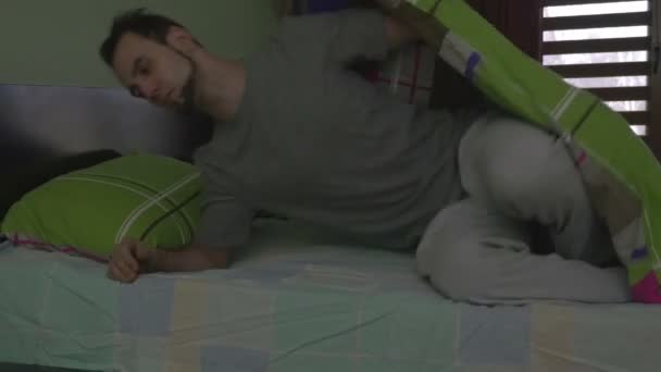 Junger schöner Mann zieht die Decke und schläft — Stockvideo