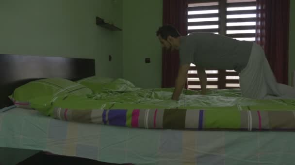 Young handsome man throwing himself in bed and sleeping — Stock Video