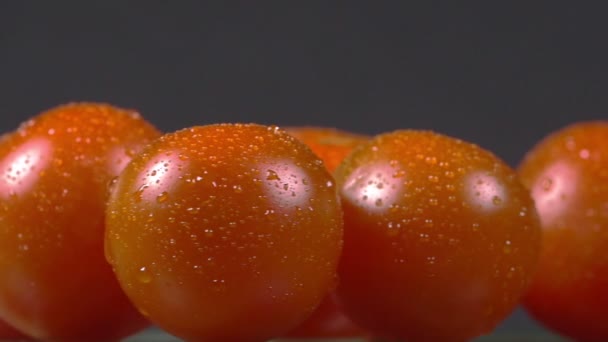 Primer plano de tomates cherry espolvoreados con agua y girando en un plato — Vídeo de stock