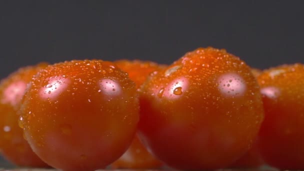 Close-up de tomates cereja polvilhados com água e girando em uma placa — Vídeo de Stock