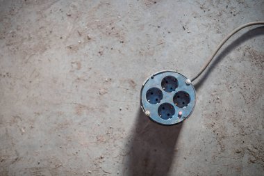 Gri beton zeminde izole edilmiş dört prizli çoklu elektrik prizleri, dört prizli güç şeridi, üst manzara.
