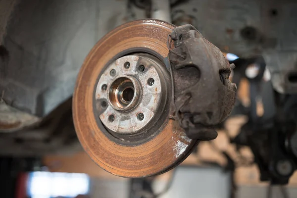 Old and rusty car's suspension parts. Rusted disc brake and caliper on the car. Automotive industry and garage concepts. Selective focus