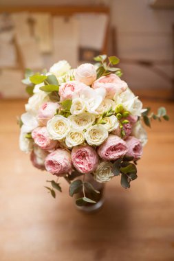 Güneşli bir günde ahşap masada beyaz ve pembe güllerle düğün buketi