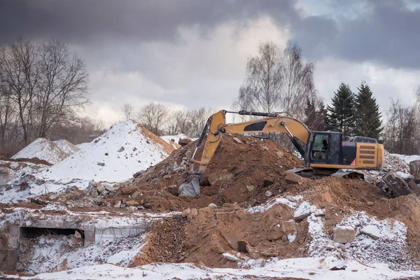 Excavator working at construction site. Backhoe digs ground for the foundation and for paving out sewer line. Construction machinery for excavating, loading, lifting and hauling of cargo on job sites