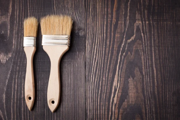 Paint brushes on old wooden background — Stock Photo, Image