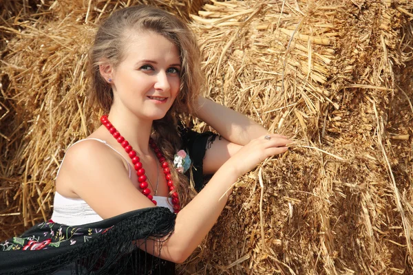 Beautiful young woman in a white sundress near haystack — Stock Photo, Image