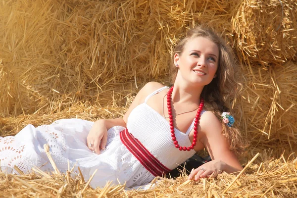 Beautiful young woman lying on a haystack — Stock Photo, Image