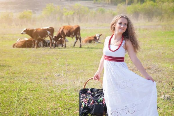 Giovane bella donna in lungo prendisole bianco con un cesto — Foto Stock