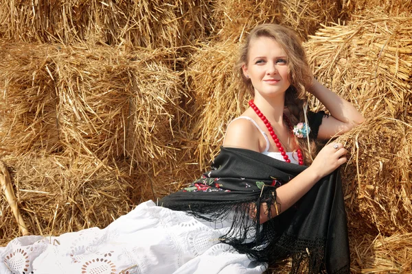 Mooie jonge vrouw in een witte sundress in de buurt van hooiberg — Stockfoto