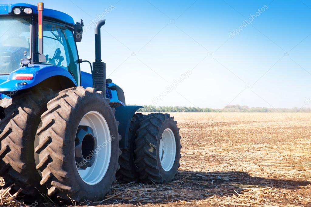 Blue tractor on the background of an empty field 