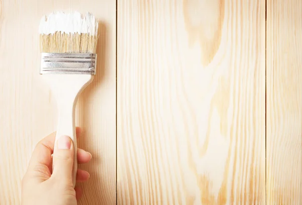 Brush with white paint in hand — Stock Photo, Image