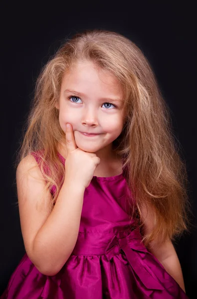 Kleine schattige peinzende meisje in een helder roze jurk — Stockfoto