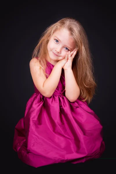 Pequena menina bonito sentado no chão em um vestido rosa — Fotografia de Stock