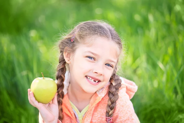 Douce fille avec une dent tombée tenant une pomme dans sa main — Photo