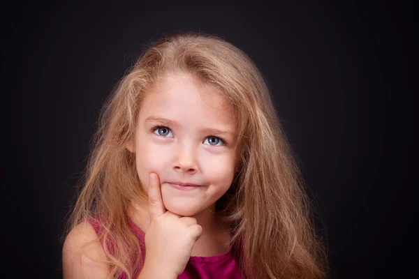 Kleine schattige peinzende meisje in een helder roze jurk — Stockfoto