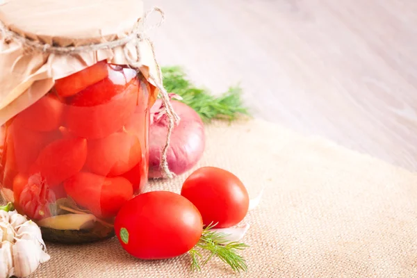 Tomaten in Dosen mit Knoblauch und Kräutern in einem Glas auf dem Tisch — Stockfoto