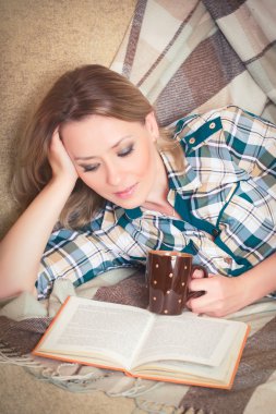 Genç güzel kadın kanepede yatan okuma