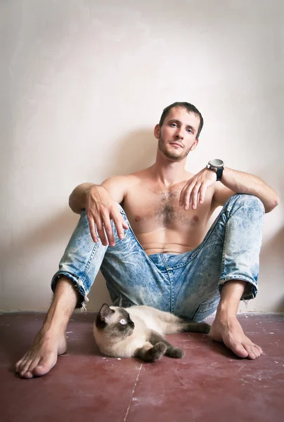 Young man sitting on the floor with his cat — Stock Photo, Image