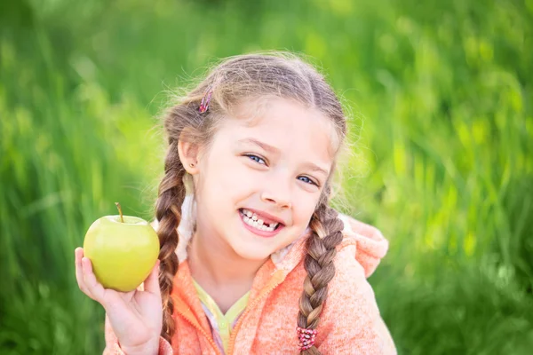 Douce fille avec une dent tombée tenant une pomme dans sa main — Photo