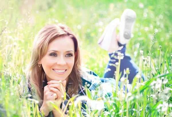 Portrait of a beautiful young woman lying in the grass — Stock Photo, Image