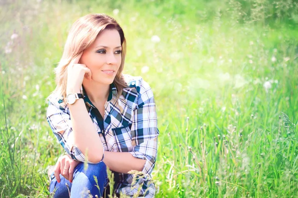 草の中に座っている美しい若い女性の肖像画 — ストック写真