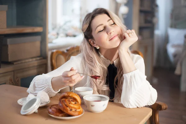 Mladá žena snídá čaj a pečivo s marmeládou. — Stock fotografie