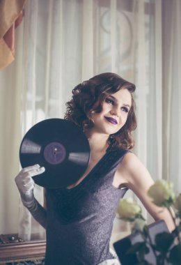 Geçmişe dönük, plak plaklı güzel bir kadın. Eski moda iç mekan. Stüdyo fotoğrafı.