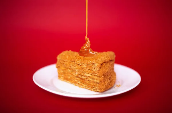 Klasyczne ciasto z kremem karmelowym na czerwonym tle. — Zdjęcie stockowe