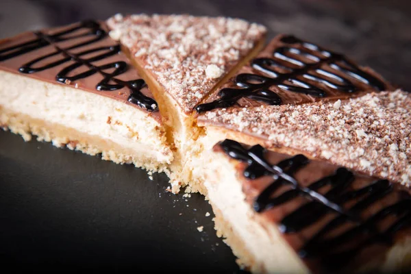 Cheesecake fatiado com cacau e molho de chocolate close-up na mesa. — Fotografia de Stock
