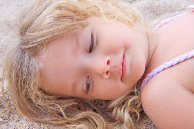 küçük kız kumun üzerinde yalan