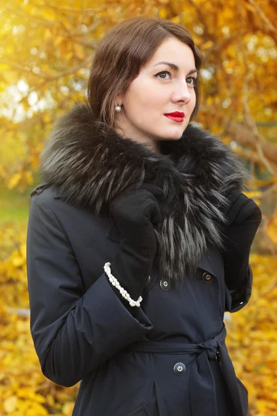Mulher em um casaco preto no fundo da árvore de outono — Fotografia de Stock